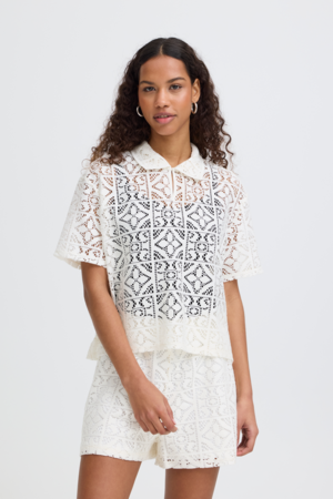 Model draagt zwarte lace top met jeans en tas – casual styling